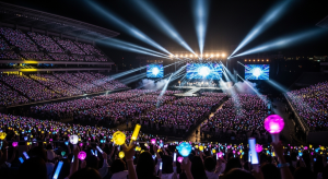 A group of K-pop performers dancing on stage under colorful lights